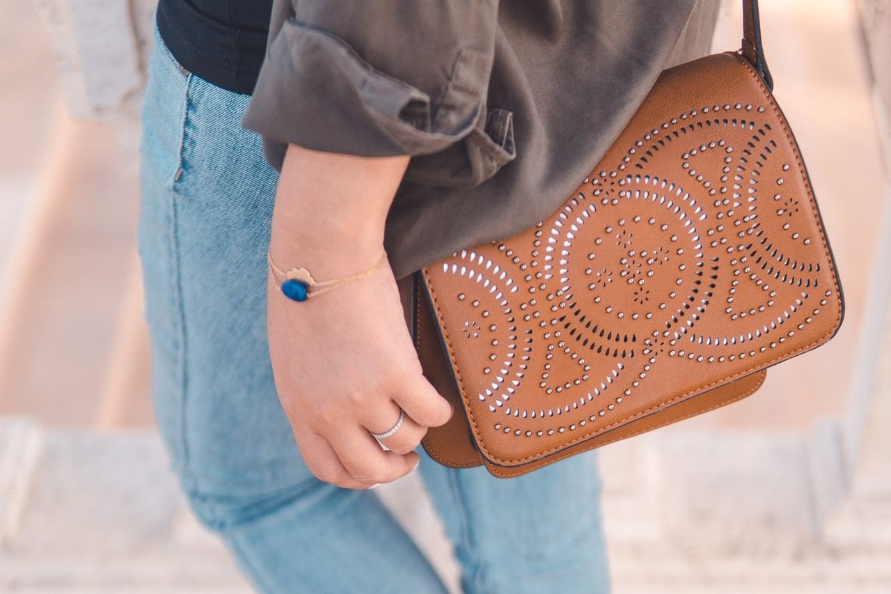 Woman on her way to a date, wearings a gold and lapis bracelet and a diamond fashion ring along with a leather purse jeans, and button down shirt.