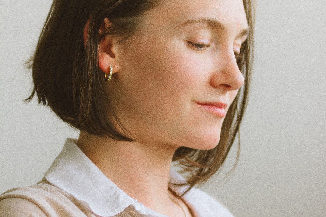 a woman at the office wears a pair of diamond huggies earrings.
