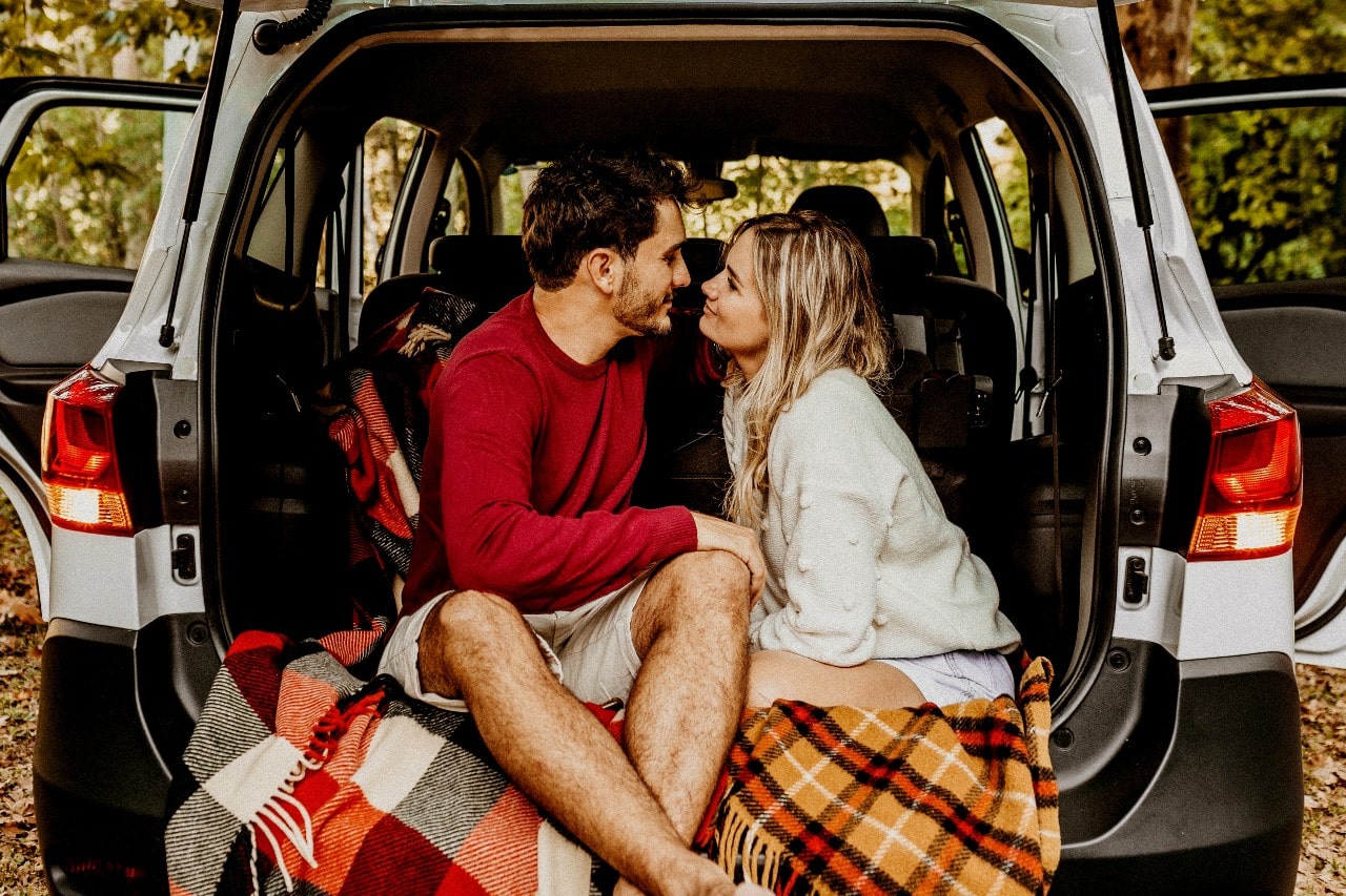 a couple sitting in the back of an SUV smiling at each other