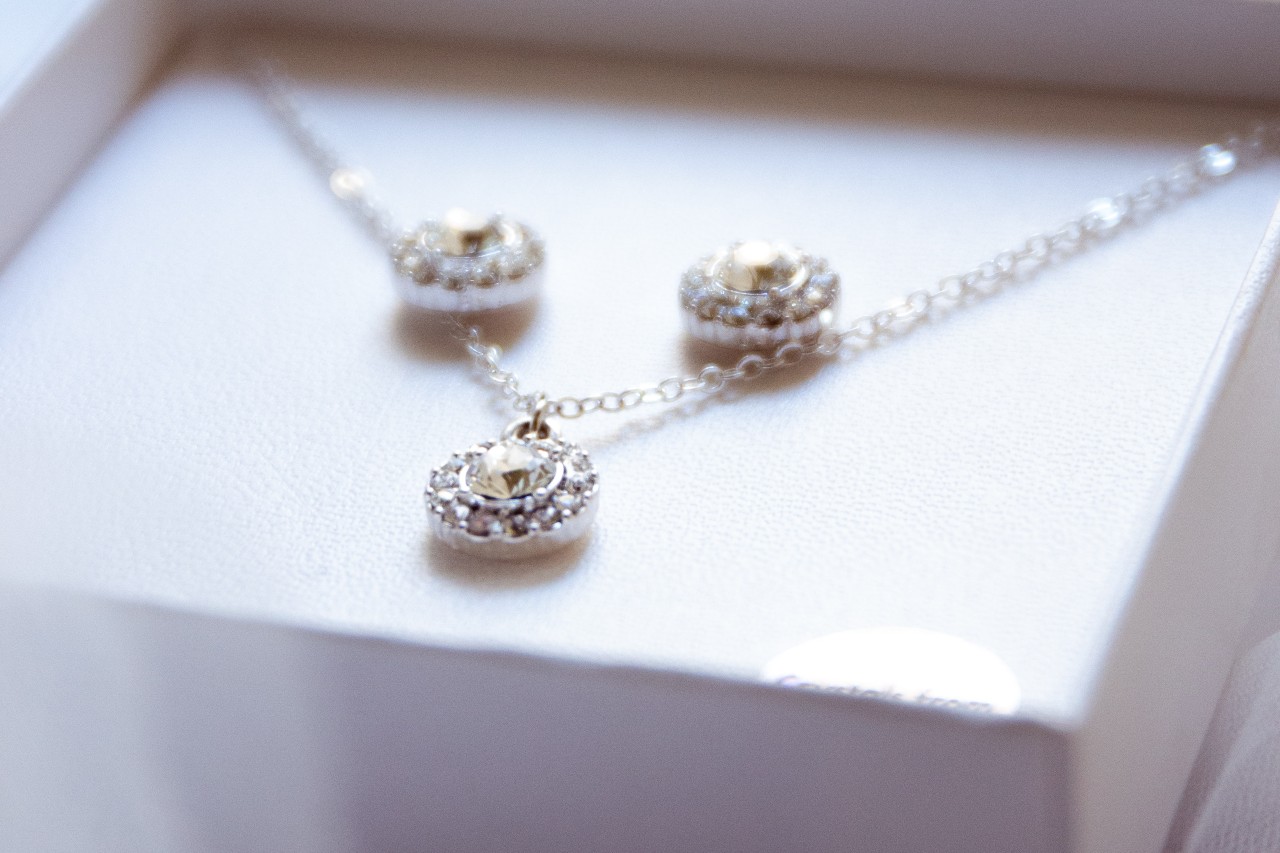 A close-up of a matching diamond necklace and earring set in a white jewelry box.