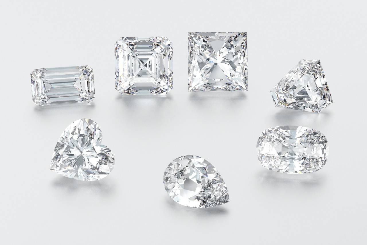 A close-up of seven diamonds with different cuts on a pale surface