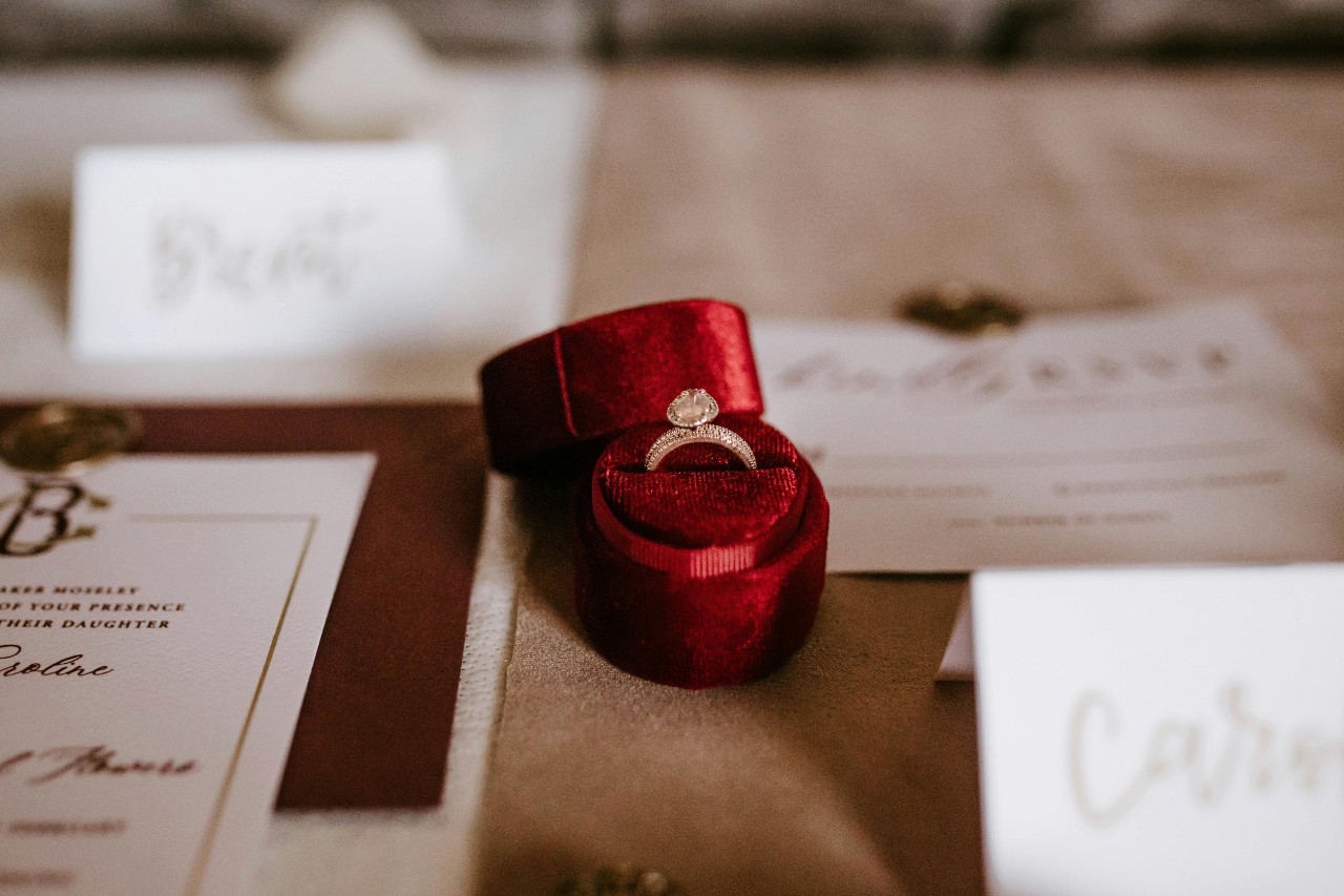 an engagement ring in a red ring box on a table set at a wedding reception