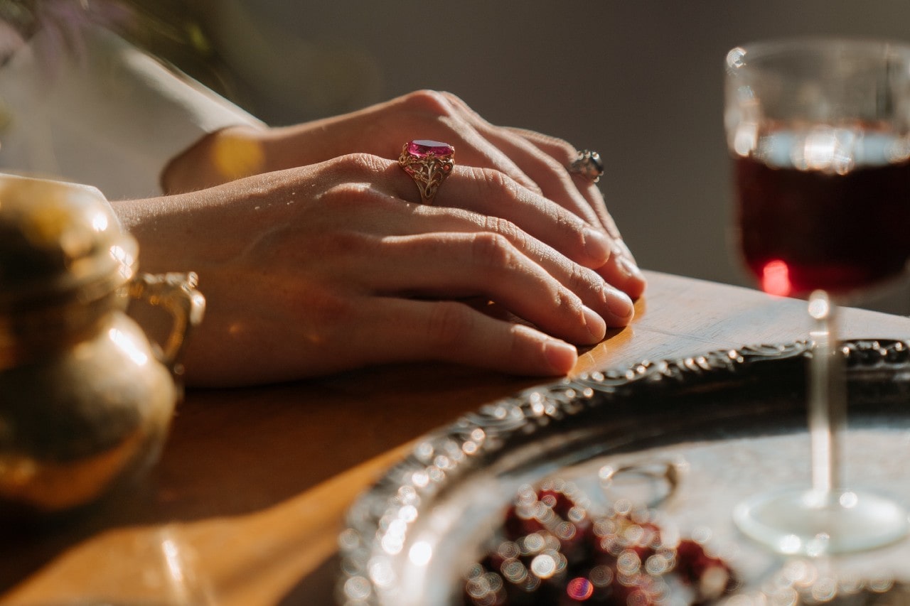 a woman’s hand resting on nicely set table and wearing gemstone fashion rings