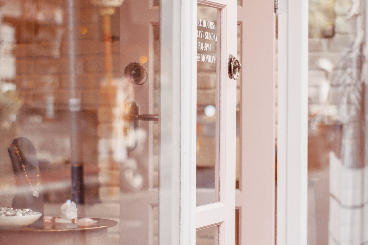 A softly lit jewelry boutique stand is seen through glass doors, with display pieces visible inside.