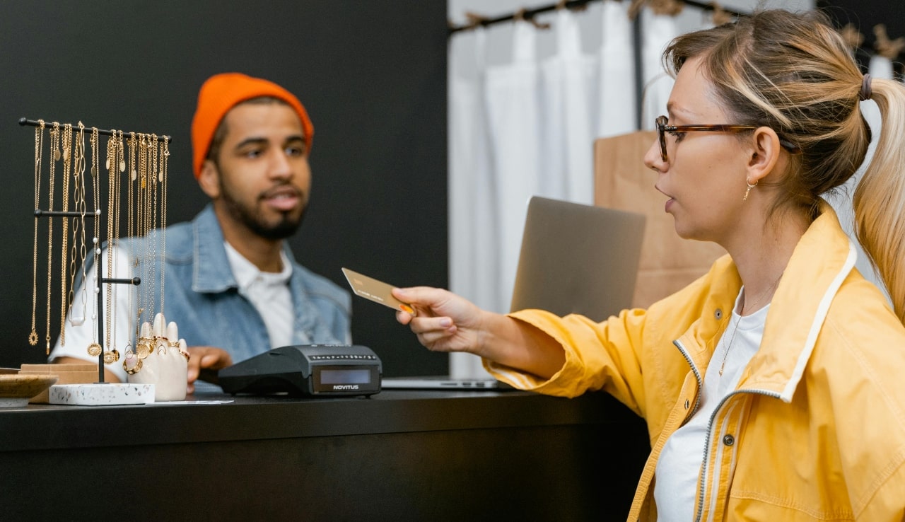 A close up of a woman in yellow jacket paying with card on a cash desk.