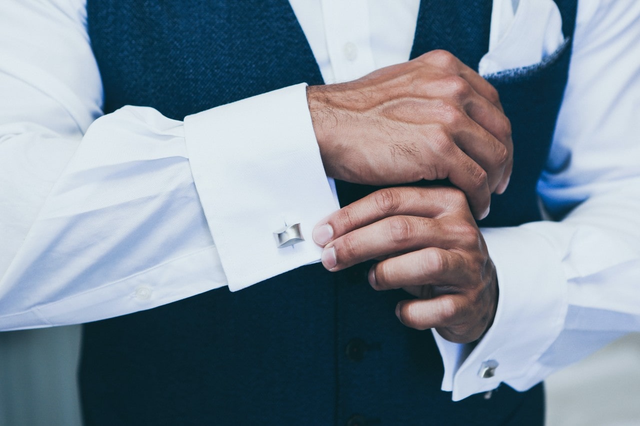 A close-up of a wall-dressed man adjusting his shirt cuffs adorned with elegant cufflinks. A close-up of a wall-dressed man adjusting his shirt cuffs adorned with elegant cufflinks.