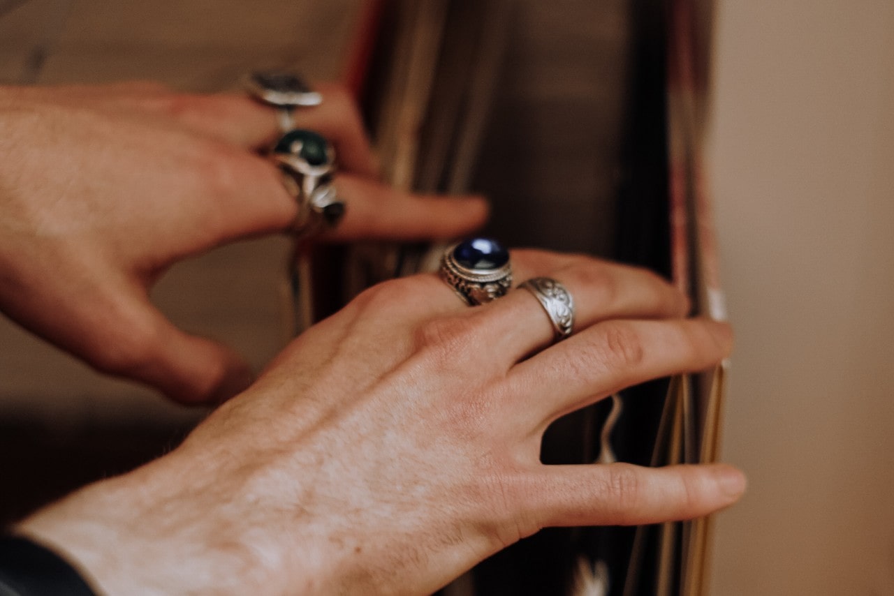 A pair of hands looking through a portfolio and wearing four silver fashion rings