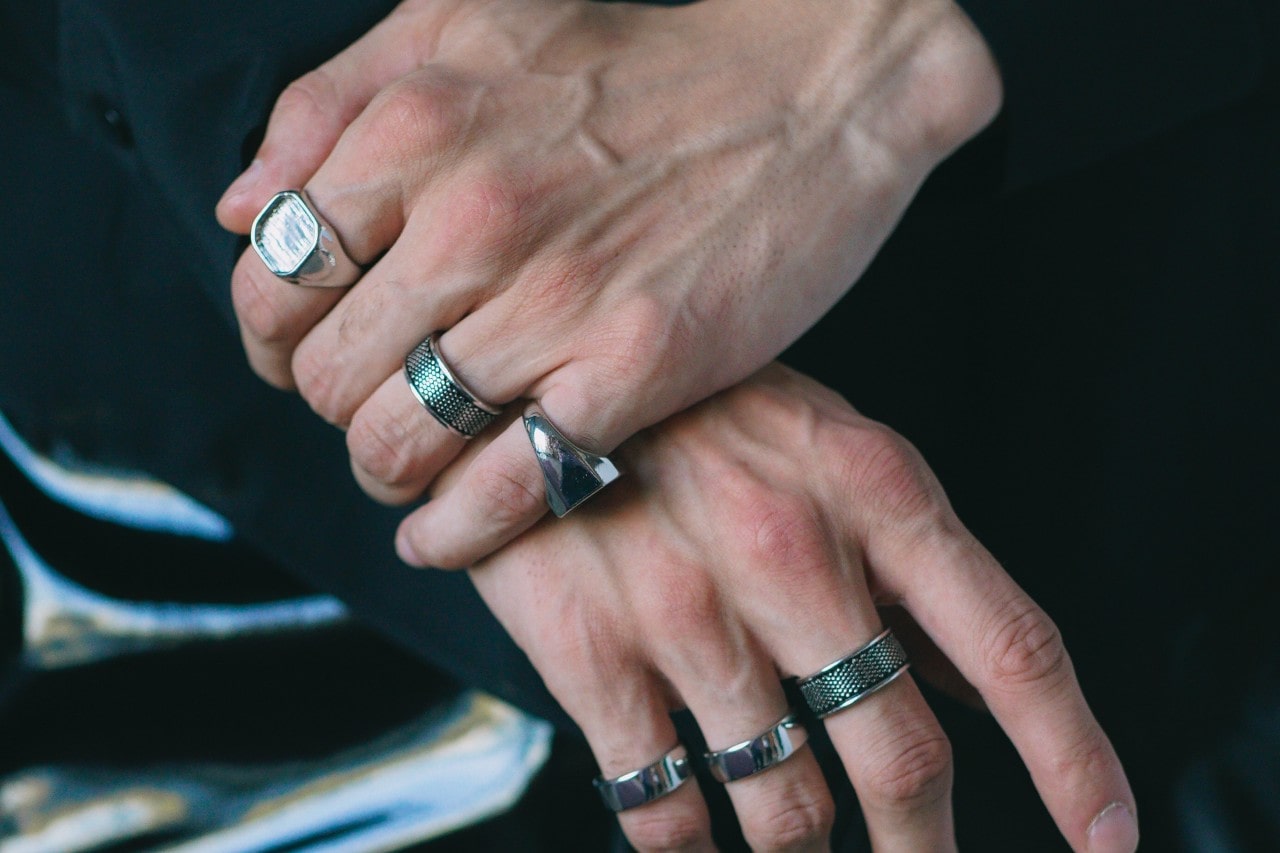 a pair of hands wearing a number of silver fashion rings.