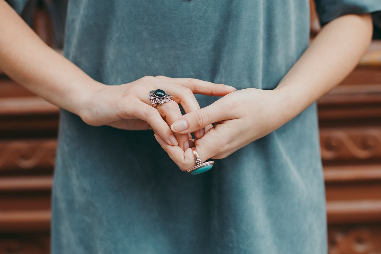 a pair of lady’s hands wearing blue fashion rings and blue clothing