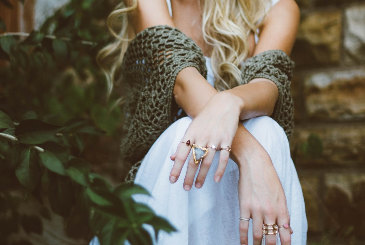torso shot of a lady wearing fashion rings and elegant clothing