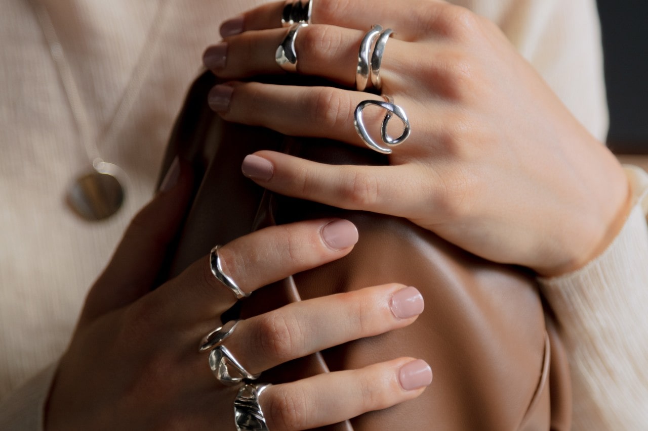 A woman holds her leather purse while showing off her white gold rings.