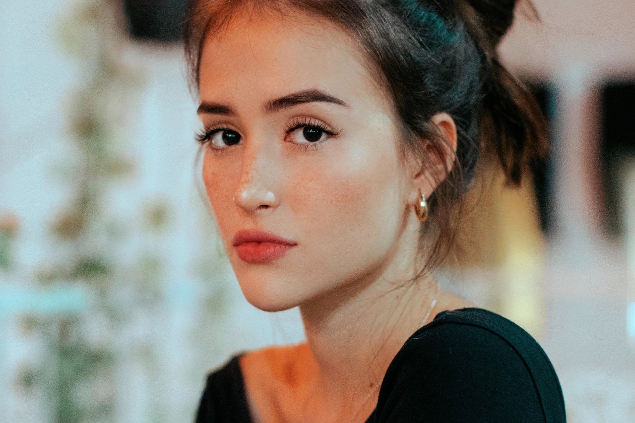 a young woman wearing gold huggies earrings and a dainty chain necklace. a young woman wearing gold huggies earrings and a dainty chain necklace.