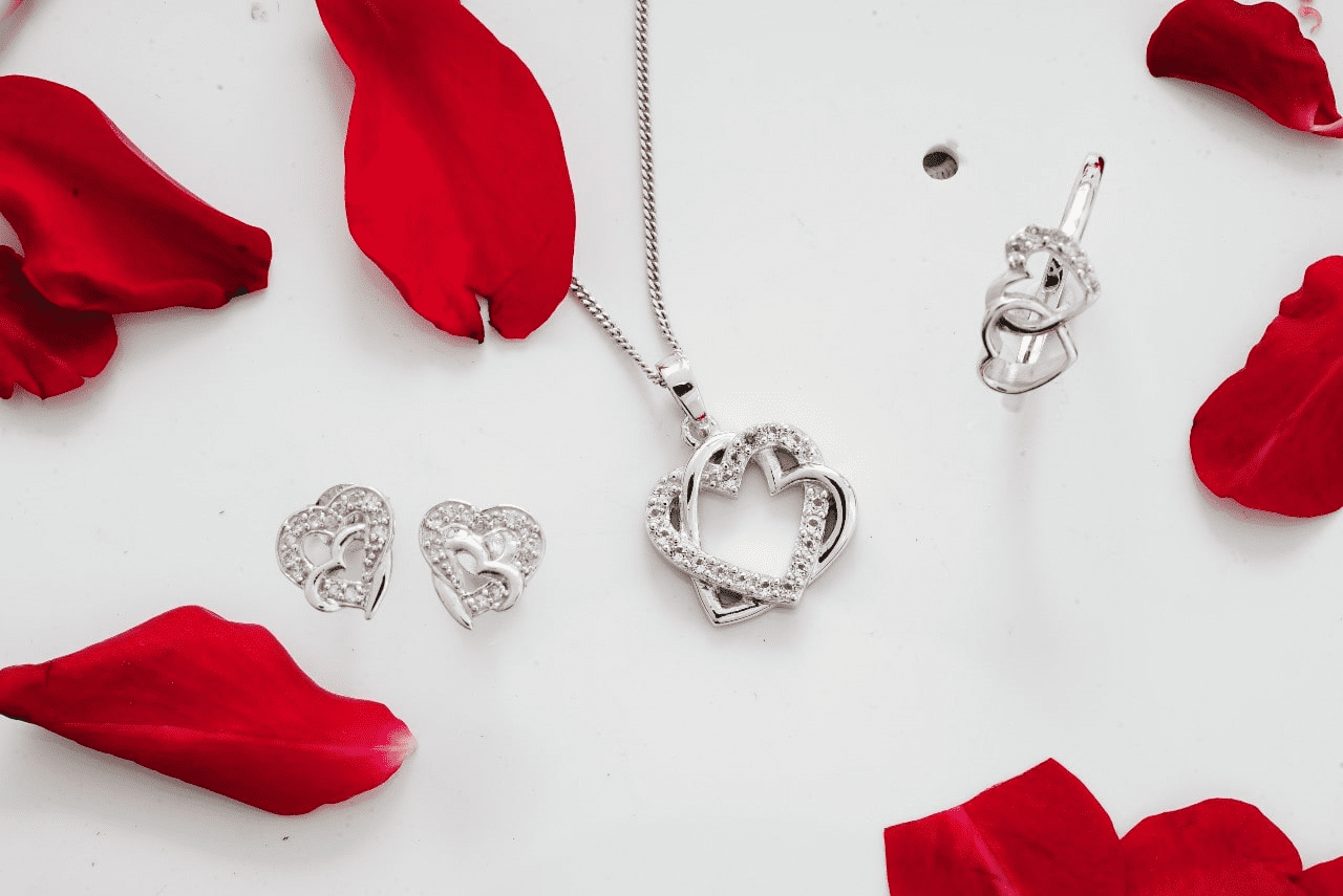 an assortment of necklaces displayed beside flower petals