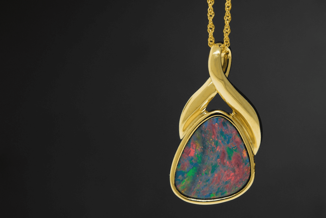 close-up of a yellow gold and opal fashion necklace on a black background