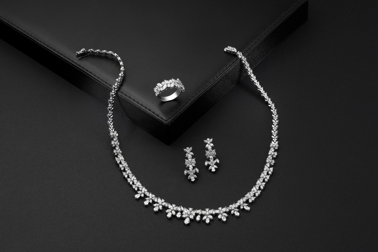 A close up of a diamond set on a black surface, including drop earrings, necklace and fashion ring
