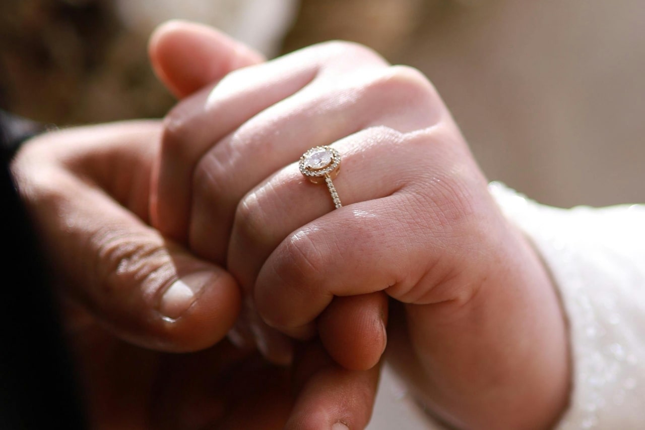 A close-up of a couple holding hands, with focus on the elegant engagement ring on her hand. A close-up of a couple holding hands, with focus on the elegant engagement ring on her hand.