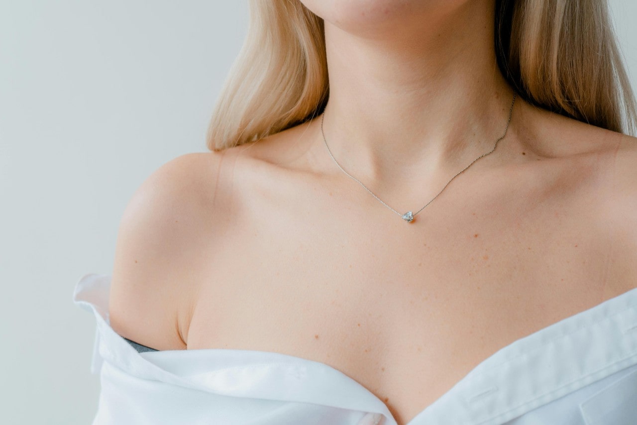 A close-up of a woman’s neck wearing a diamond necklace. A close-up of a woman’s neck wearing a diamond necklace.