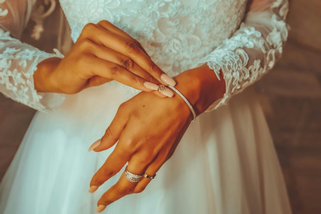 A close-up of a bride putting on a white gold diamond bangle bracelet. A close-up of a bride putting on a white gold diamond bangle bracelet.