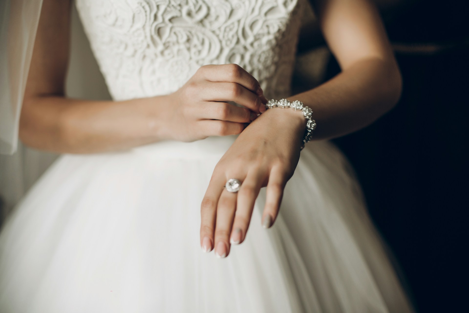 A close-up bride putting a diamond bracelet onto her wrist on her wedding day. A close-up bride putting a diamond bracelet onto her wrist on her wedding day.