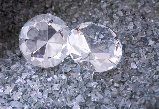 A pair of round cut diamonds sitting among crushed glass.