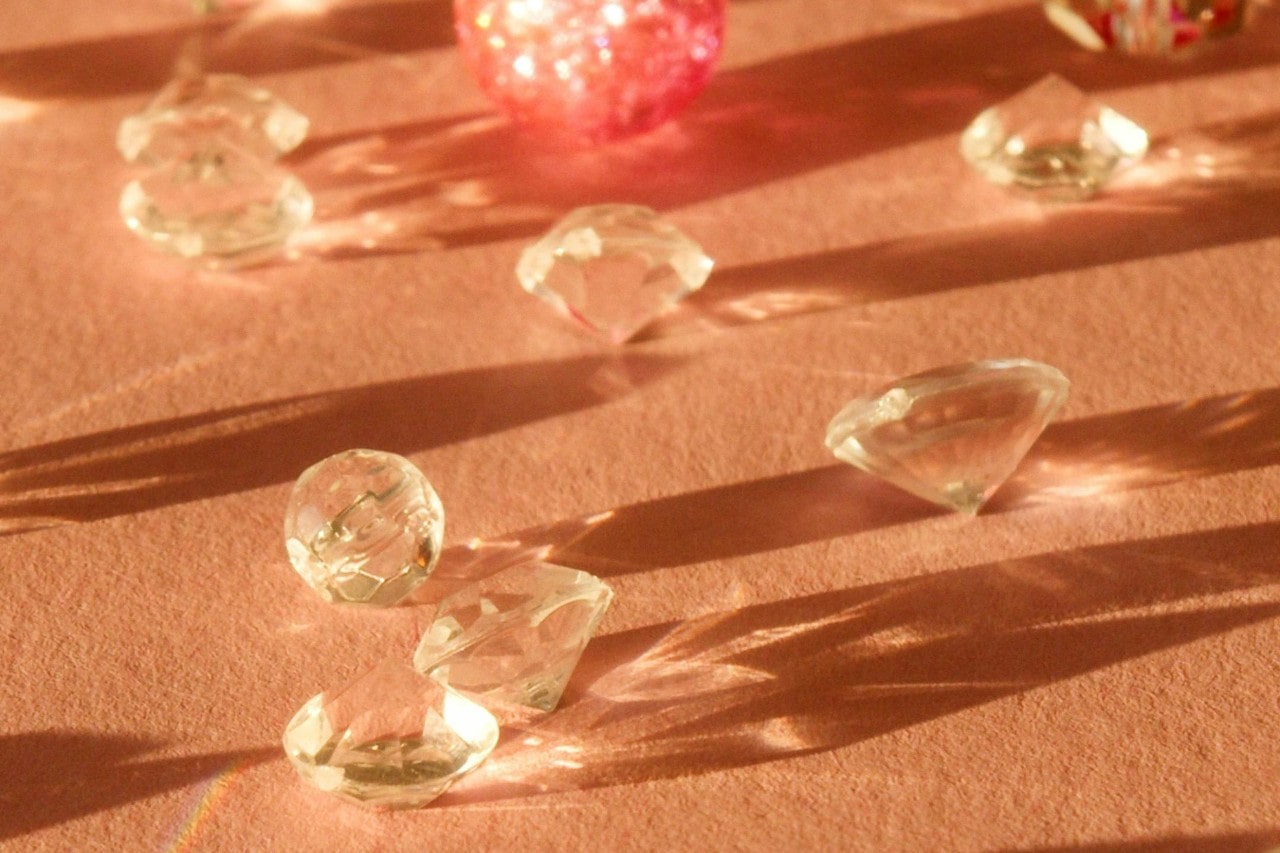 Many diamonds sit on an orange surface in the sunlight.