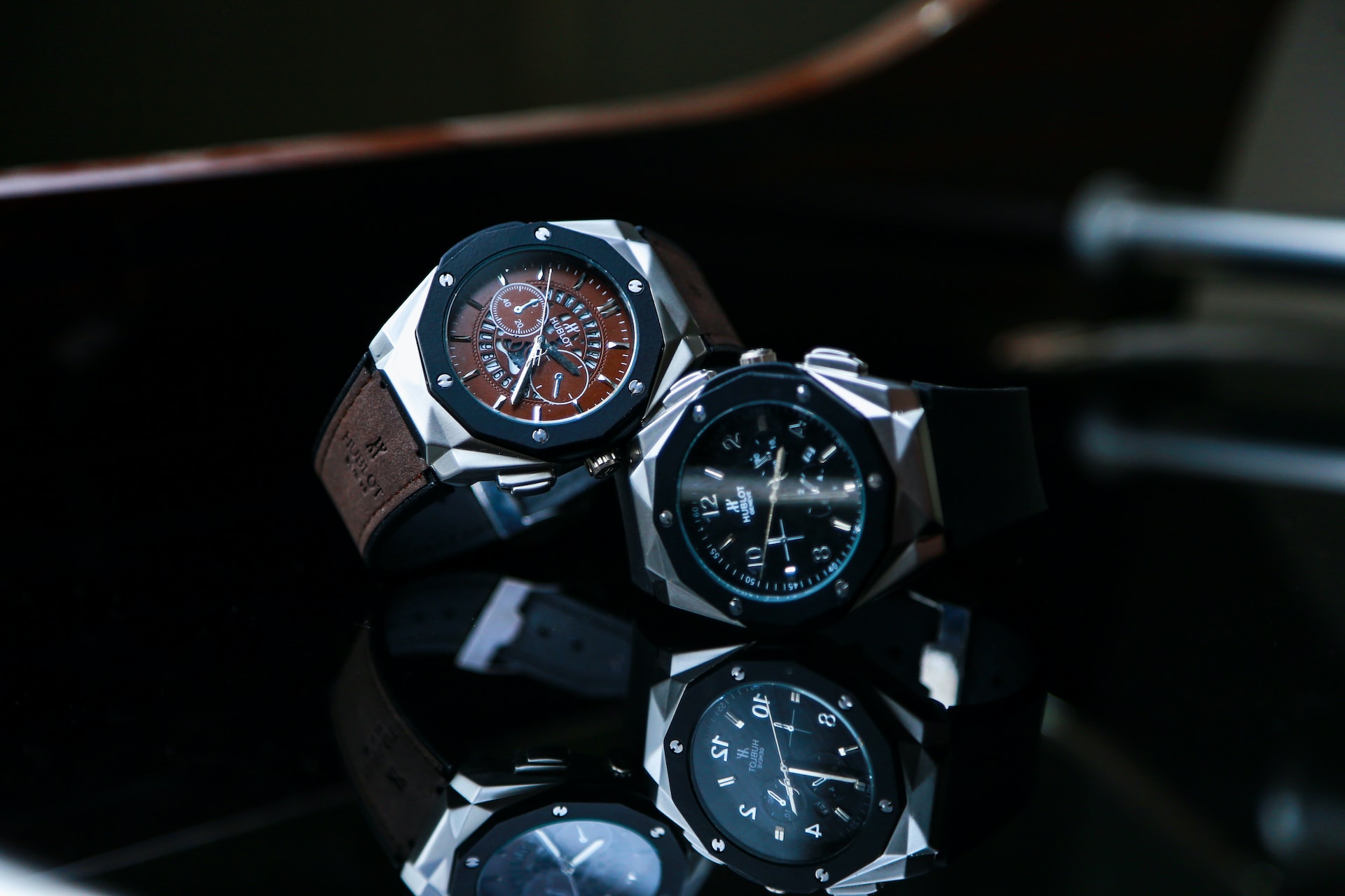 Two elegant wristwatches, one has a brown leather strap, the other a black rubber strap, are side by side on a glossy surface, casting reflections. Two elegant wristwatches, one has a brown leather strap, the other a black rubber strap, are side by side on a glossy surface, casting reflections.
