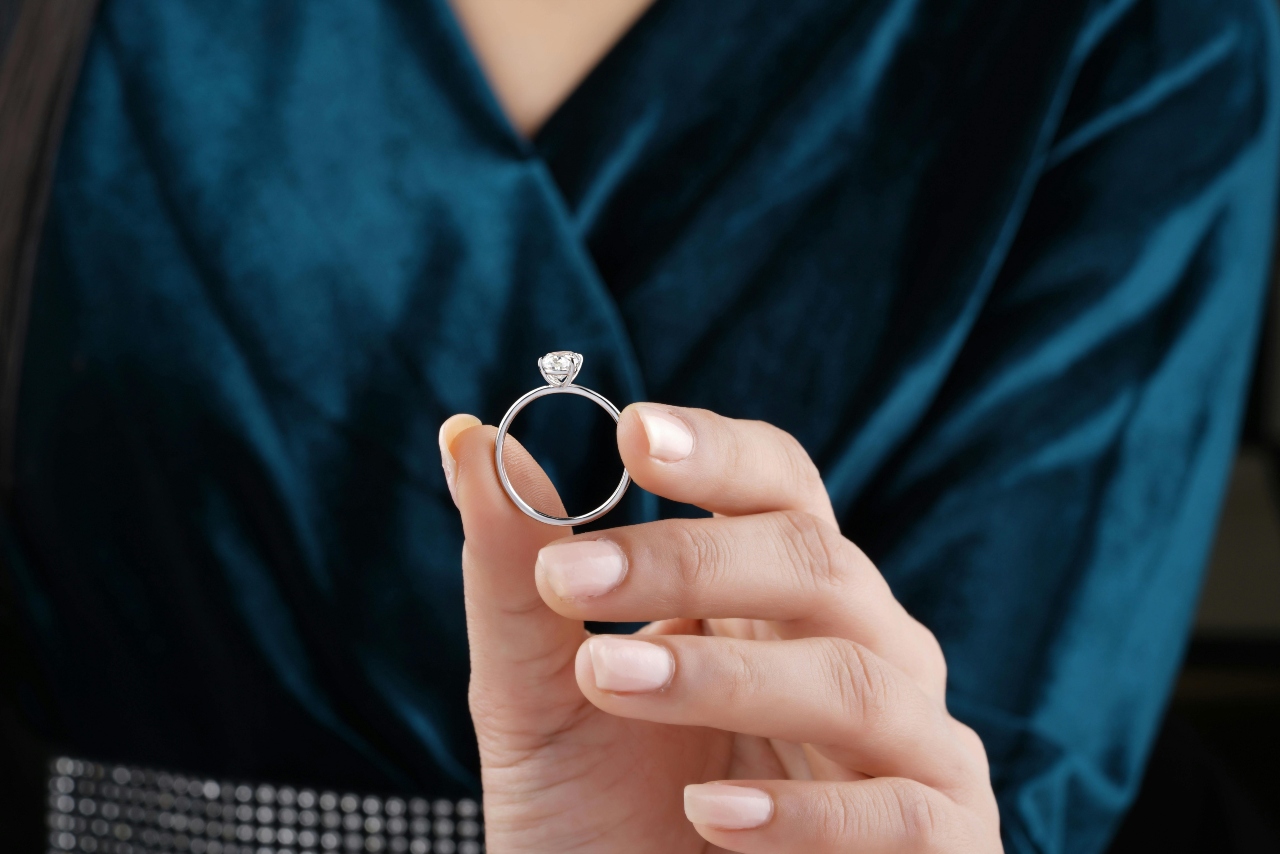 A close-up of a person holding a simple yet elegant solitaire engagement ring. A close-up of a person holding a simple yet elegant solitaire engagement ring.