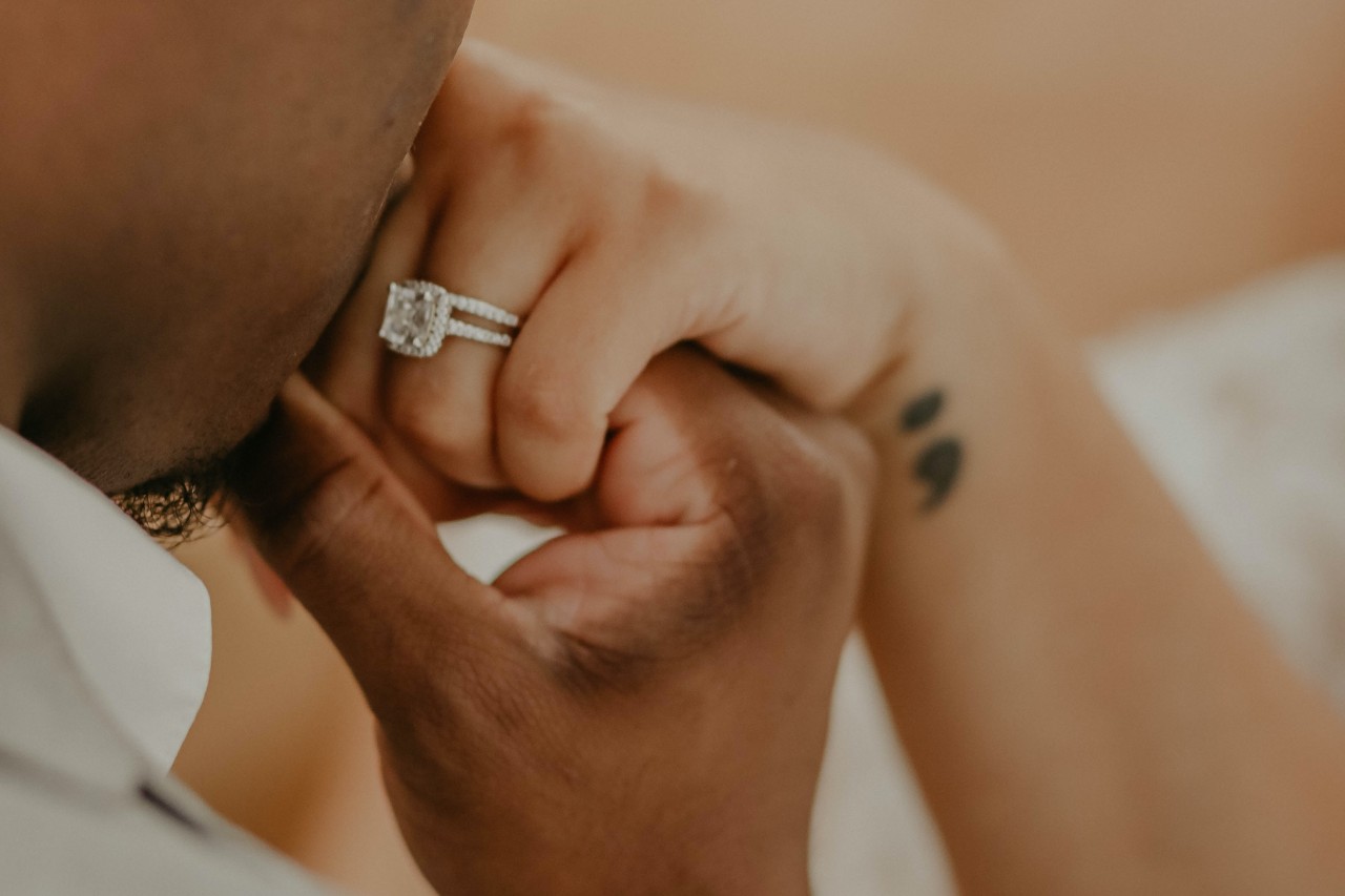 a man kissing a woman’s hand wearing an engagement ring