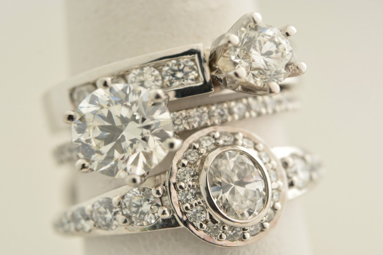 three diamond engagement rings on a light background